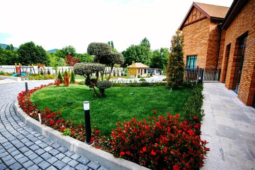 a garden with red flowers and a brick building at Hill Chalet Hotel Gabala in Gabala