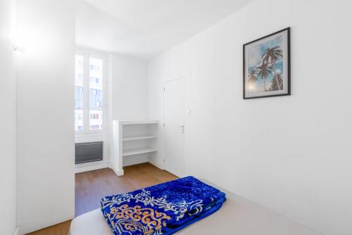 une pièce blanche avec un coussin bleu sur un canapé dans l'établissement Joli appartement 2 pièces proche gare St Charles, à Marseille