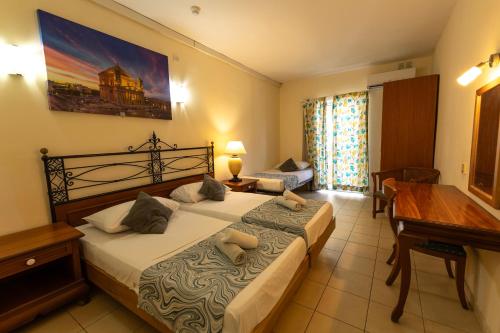 a bedroom with a bed and a desk and a piano at Qawra Point Holiday Complex in St Paul's Bay