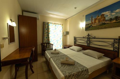 1 dormitorio con 1 cama con escritorio y una pintura en la pared en Qawra Point Holiday Complex, en St Paul's Bay