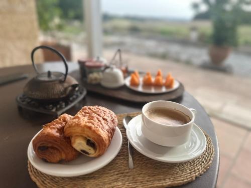 een tafel met een kopje koffie en een croissant bij Domaine Léa Chanflaur - Spa - La maison du bonheur in Terraube
