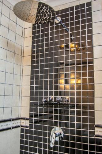 a shower with a black and white tiled wall at Ocean Dream Beach Cottage in Swakopmund