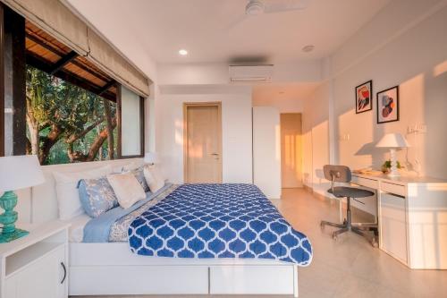 a bedroom with a bed and a desk and a window at Quaint & Picturesque 2BHK Apartment by tisyastays in Candolim