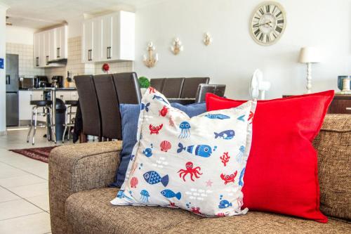 a couch with red and blue pillows in a living room at Ocean Dream Beach Cottage in Swakopmund