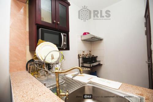 a kitchen counter with a sink and a microwave at Résidence Le Sommet Douala in Douala