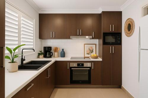 a kitchen with brown cabinets and a sink at Peaceful 2BR Villa Shops & Parks Ingleburn in Ingleburn
