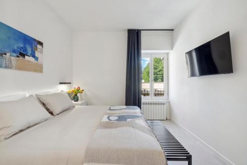 a white bedroom with a bed and a tv at Casa Matilde in Baveno