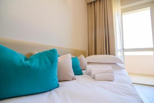 a white bed with blue and white pillows on it at Grand Hotel President in Siderno Marina