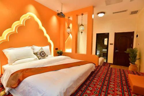 a bedroom with a large bed with an orange wall at Ancient Road Yunju in Kashgar