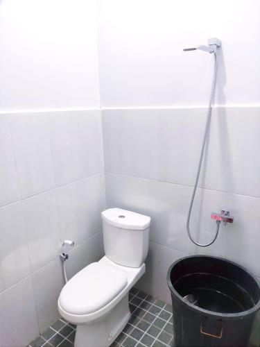 a bathroom with a toilet and a black bucket at Denisa homestay Kuningan 2 in Mantaak