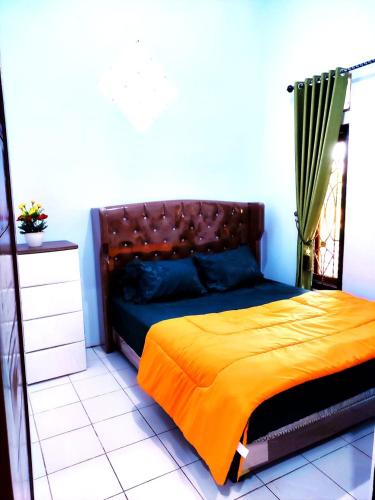 a bedroom with a bed with an orange blanket at Denisa homestay Kuningan 2 in Mantaak