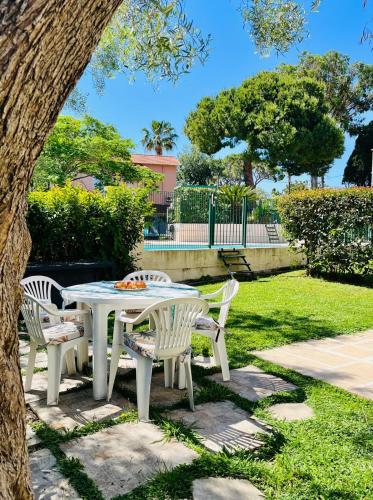une table et des chaises blanches sous un arbre dans l'établissement Exclusive 80 sqm apartment with private garden and terrace on the Cap d Antibes, 300 mt from sandy Plage de la Salis, à Antibes