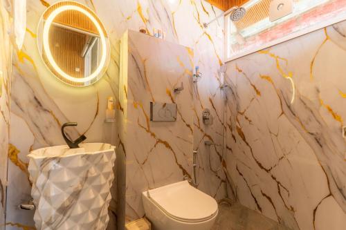 a bathroom with a toilet and a mirror at StayVista at Silver Slopes with outdoor pool in Chandīgarh