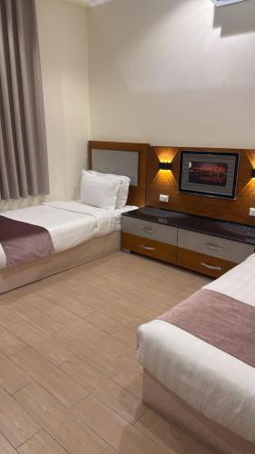 a hotel room with two beds and a flat screen tv at أصداء البحر للشقق المخدومة in Yanbu