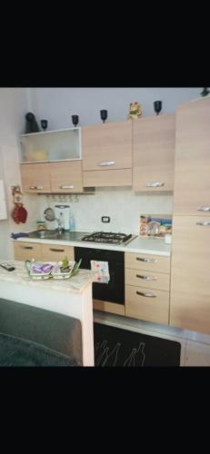 a kitchen with wooden cabinets and a stove top oven at Favoloso Appartamento a torvainica in Torvaianica