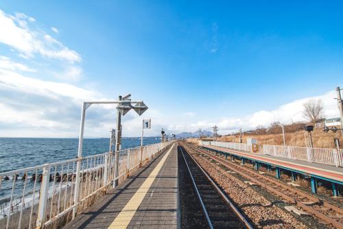 a train track next to the ocean on a pier at 北海道伊達の海辺ヴィラ 最大7名一棟貸切 ファミリー向け 北斎アート in Date
