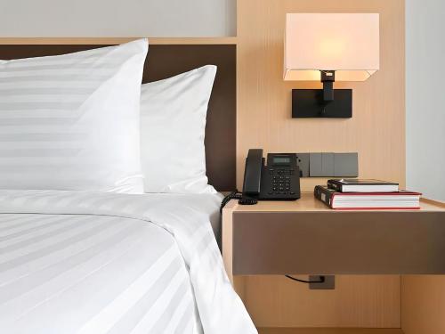 a bed with a phone next to a table with a lamp at Arena Cam Ranh Pearl Bay in Cam Ranh