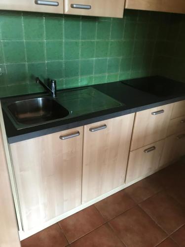 une cuisine avec un évier et un plan de travail noir dans l'établissement RESIDENCE SOGNU DI MARE PLAGE Marine di Bravone, à Linguizzetta