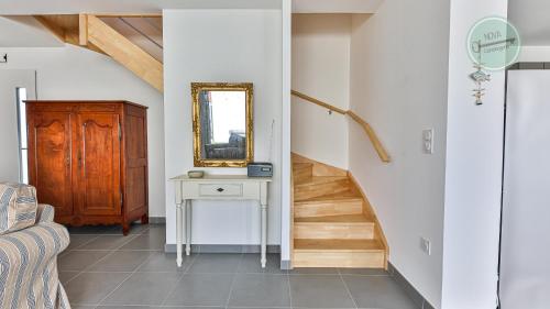 un couloir avec un escalier, un miroir et une table dans l'établissement Maison familiale rue des Cordes, à Saint-Hilaire-de-Riez