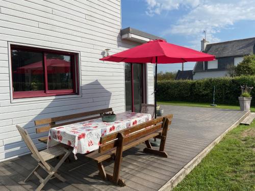 une table de pique-nique et un parasol sur une terrasse dans l'établissement La cabane de la baie, à Plounévez-Lochrist