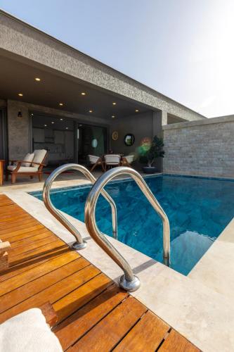 a swimming pool with a wooden deck and a house at Marje Villas Bodrum in Bodrum City