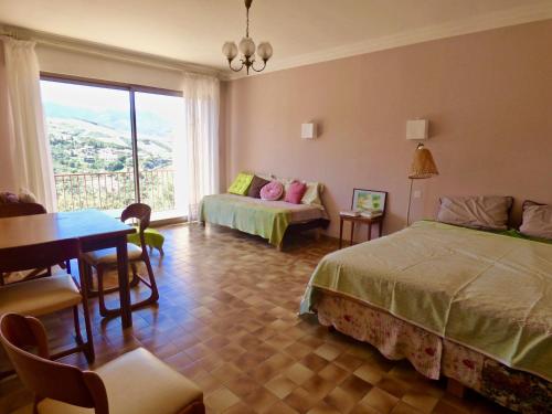 une chambre avec deux lits et une table et une fenêtre dans l'établissement Magnifique Villa Vues Mer et Montagne, à Banyuls-sur-Mer