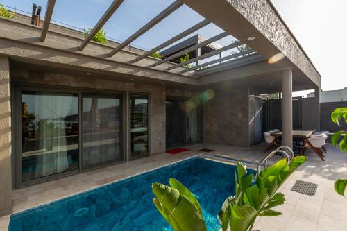 an outdoor pool with a pergola and a house at Marje Villas Bodrum in Bodrum City
