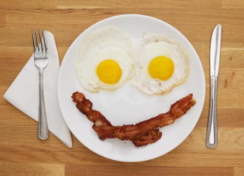 a plate with two eggs and bacon on a table at Hotel Utpala in Gangtok