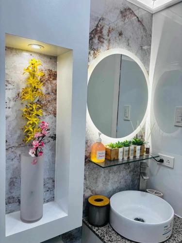 a bathroom with a toilet and a round mirror at Holiday Escape Philippines in Manila