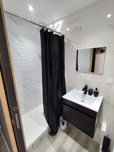 La salle de bains est pourvue d'un rideau de douche noir et d'un lavabo. dans l'établissement Maison T3, à La Seyne-sur-Mer