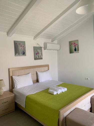 a bedroom with a bed with a green blanket at Mussels apartments in Ksamil