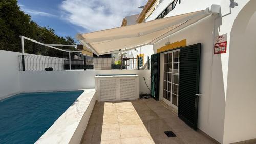 a white house with a swimming pool and an awning at BS House - Manta Rota in Manta Rota