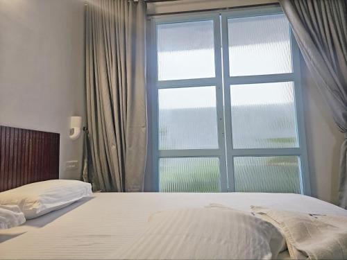 ein Schlafzimmer mit einem Bett und einem großen Fenster in der Unterkunft Cliff End Beach Stay in Kappil