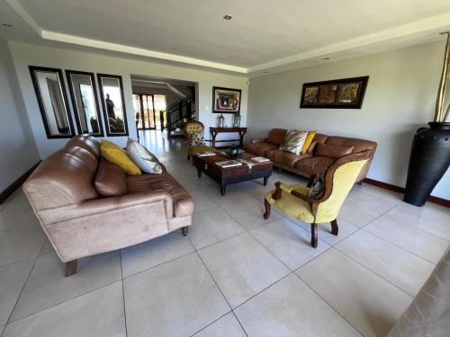 a living room with leather couches and chairs at Kalashe Bed & Breakfast in East London