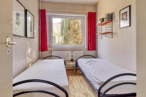 two beds in a room with a window at Appartement in Cadzand