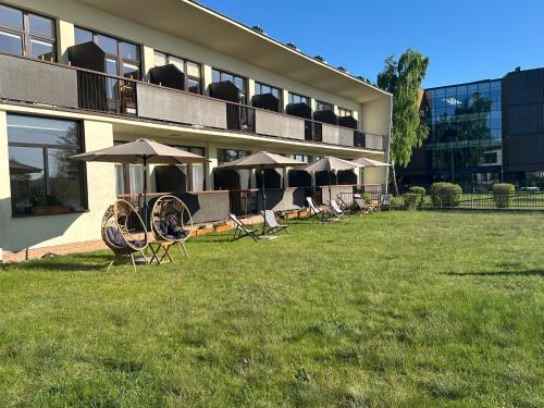 a row of chairs and umbrellas in front of a building at KAMERALNY przy promenadzie - pokoje in Charzykowy