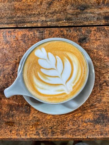 a cup of coffee sitting on a wooden table at Agra Arugambay in Arugam Bay