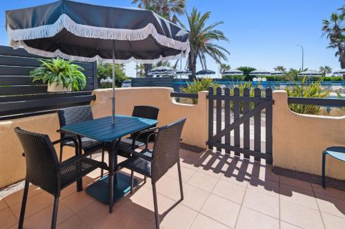 a table and chairs with an umbrella on a patio at Hôtel La Nartelle in Sainte-Maxime