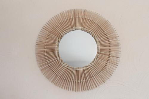 a rattan mirror hanging on a wall at Hôtel La Nartelle in Sainte-Maxime