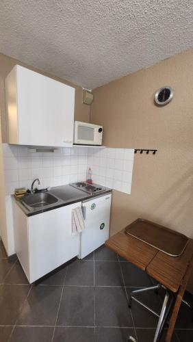une petite cuisine avec un évier et un micro-ondes dans l'établissement Studio Les logis de Paray, à Paray-le-Monial