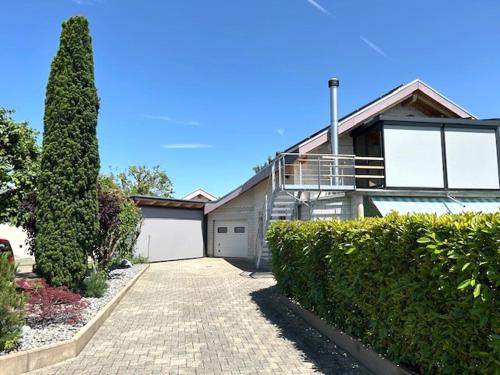a house with a garage and a tree in front of it at Au doux repos in Bure