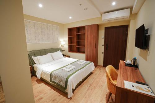 a bedroom with a bed and a desk and a television at Boutique Hotel Kviria in Tʼelavi