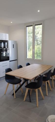 une table en bois dans une cuisine avec des chaises autour de celle-ci dans l'établissement Appartement 4 p neuf dans haut de villa , clim, parking, jardin, à Saint-Laurent-du-Var