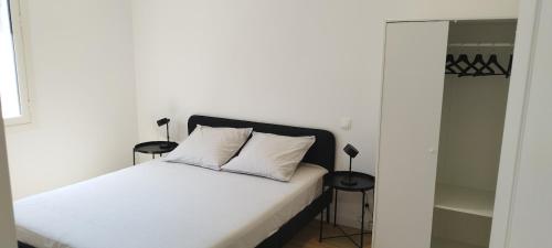une chambre avec un lit blanc avec deux tables de nuit dans l'établissement Appartement 4 p neuf dans haut de villa , clim, parking, jardin, à Saint-Laurent-du-Var