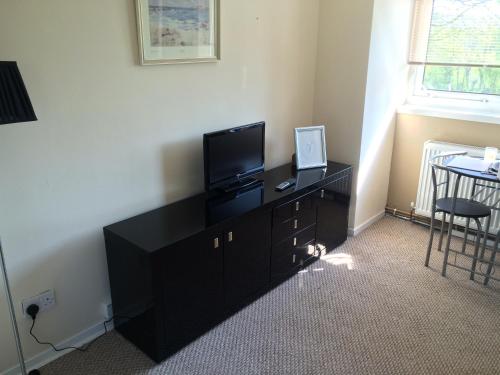 a room with a black dresser with a television on it at Kilbarchan Flat in Kilbarchan