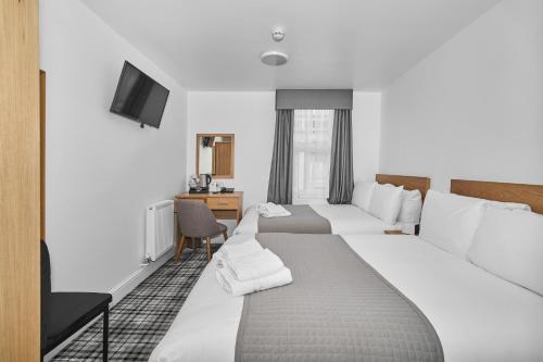 a hotel room with two beds and a television at Best Western Greater London in Ilford