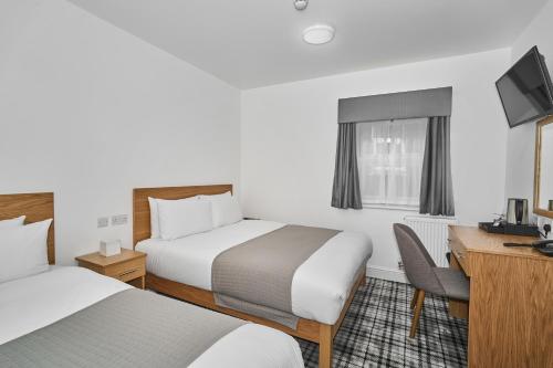 a hotel room with two beds and a desk at Best Western Greater London in Ilford