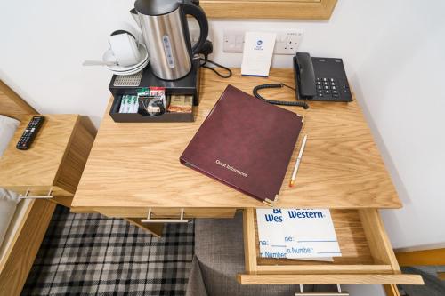 a desk with a phone and a book on it at Best Western Greater London in Ilford