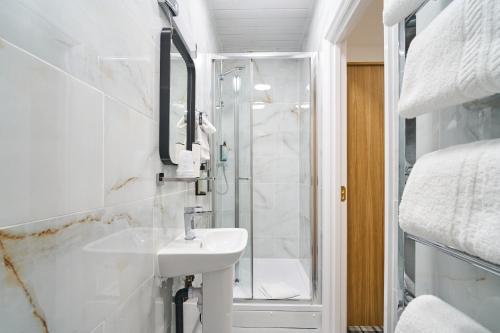 a white bathroom with a sink and a shower at Best Western Greater London in Ilford