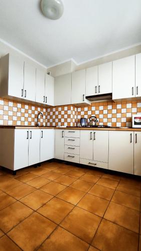 a kitchen with white cabinets and a tile floor at Василя Стуса 10 City Rooms in Bila Tserkva